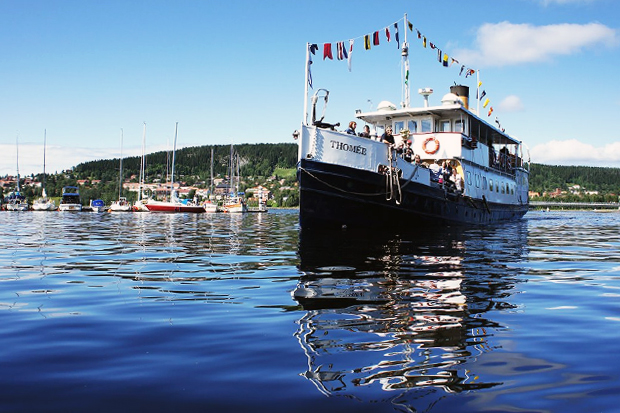 Blå himmel och blått lugnt vatten med båten Thomée i mitten som speglar av sig mot vattnet