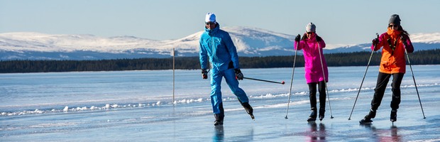 Skridskoåkare på Storsjöns is med fjällen i bakgrunden