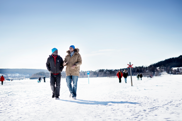Män går på isen i solskenet. De tittar på varandra.