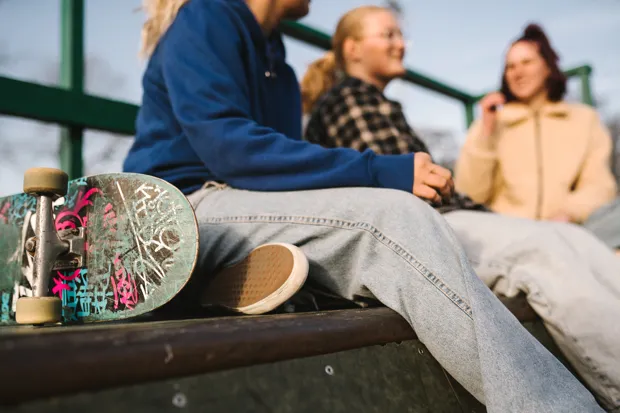 Fötter med converse-skor som dinglar över en vattenyta.