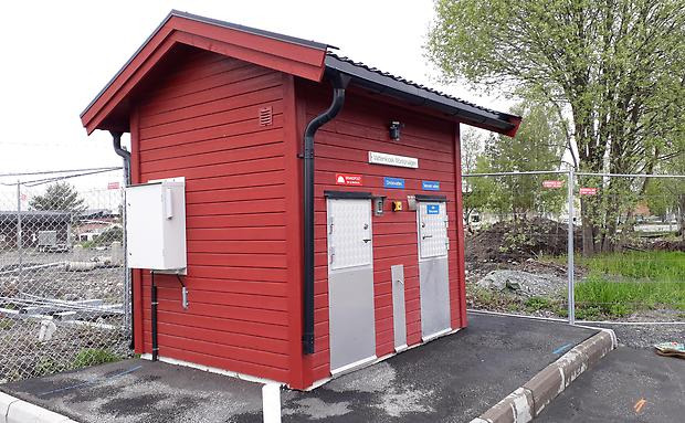 Litet rött hus med korta dörrar av metall, det är en vattenkiosk.