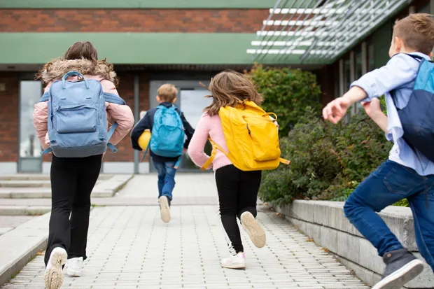 barn som springer mot en skola
