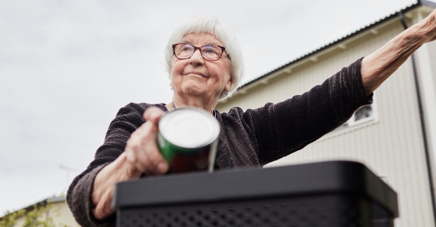 Kvinna med mössa som går mot en återvinningsstation