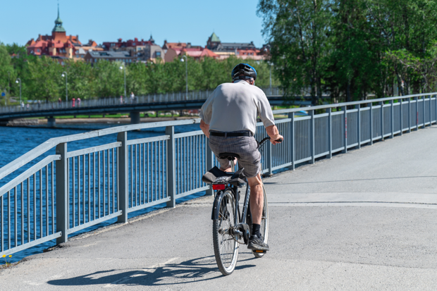 En man cyklar på bron in mot Östersund i försommargrönska.