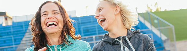 Två kvinnor är ute och motionerar och skrattar tillsammans