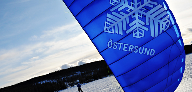 Blå kiteskärm med tryckt snöhjärta ute på isen en strålande vinterdag