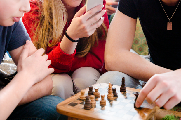 4 ungdomar spela schack, tittar pÃ¥ tv och kollar mobilen