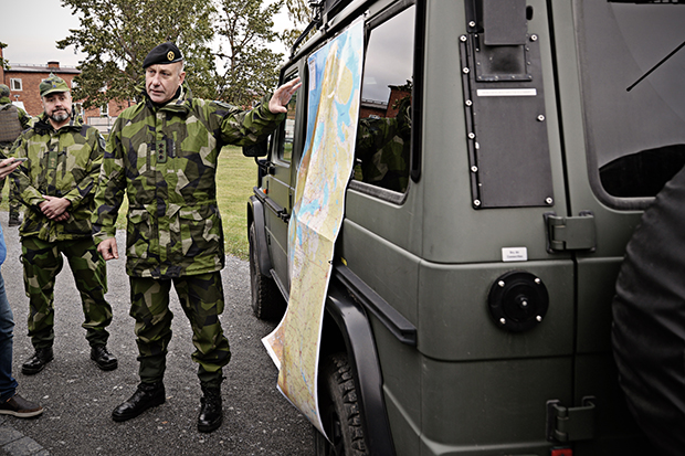 Arkivbild på militärt befäl som står vid en bil och pekar på en karta