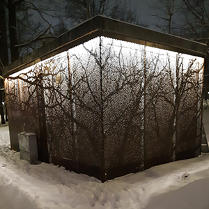 En transformatorstation i kvällsmörker med projicerade bilder av kala träd