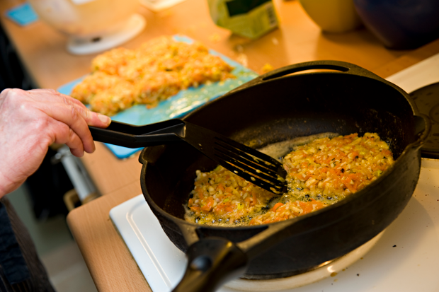 Någon steker biffar i en stekpanna. Man ser handen, en stekspade och pannan.