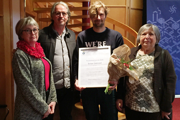 Reidun Sjövold från Tillgänglighetsrådet, Florian Stamm, ordförande i Miljö- och samhällsnämnden, Simon Jaktlund och Eva Åberg från Tillgänglighetsrådet står bredvid varandra. Simon håller ett diplom och en blombukett. .