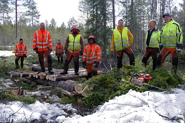 Åtta arbetsklädda män som står på en halvfärdig kavelbro.