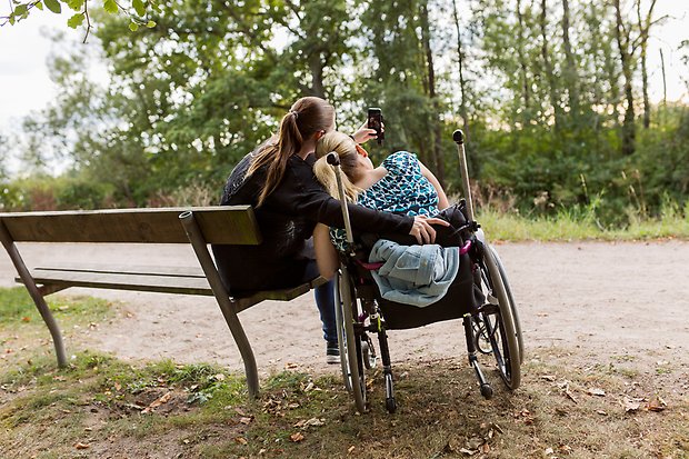 Vänner på parkbänk och i rullstol