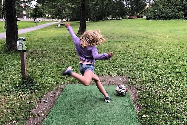 En person som spelar discgolf i en park.
