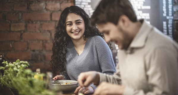 Två glada personer äter mat på restaurang