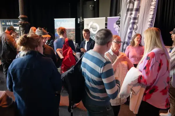 Många människor som pratar, företagsnamn i bakgrunden.