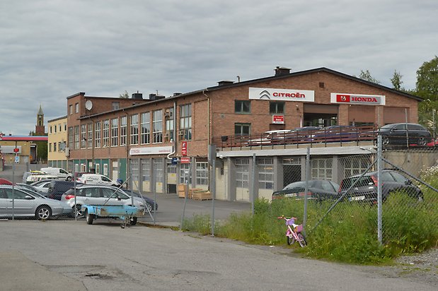 Musslan 16, Industribyggnad i brunt tegel med garageportar och stora fönster med spröjs.