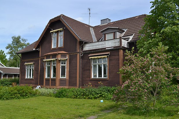 Nejlikan 6, Villa i brun träpanel och ljusbruna detaljer och brunt tegletak.