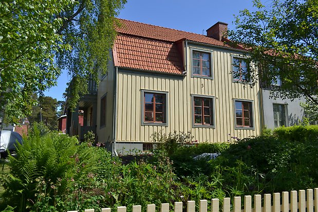 Öringen 3. Villa i grön träpanel, svarta fönster med röda spröjs.