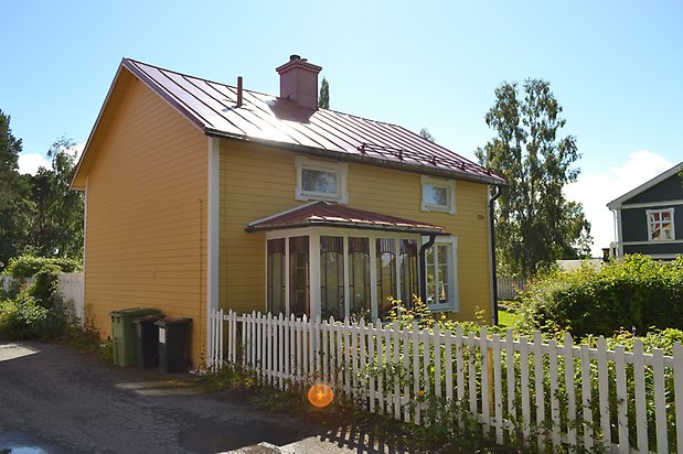 Björken 13, Villa i gul, liggande panel och punschveranda och vita fönster.