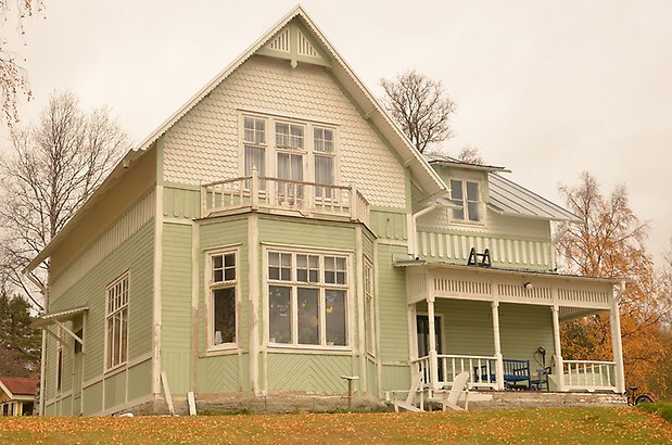 Ägostyckningen 7. Villa med ljusgrön liggande panel på nedervåningen och vit fiskfjällspanel på övervåningen. Vita fönster med spröjs. 