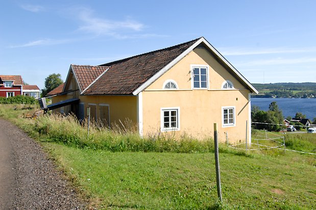 Byggnad i gul panel med vita fönster med spröjs.