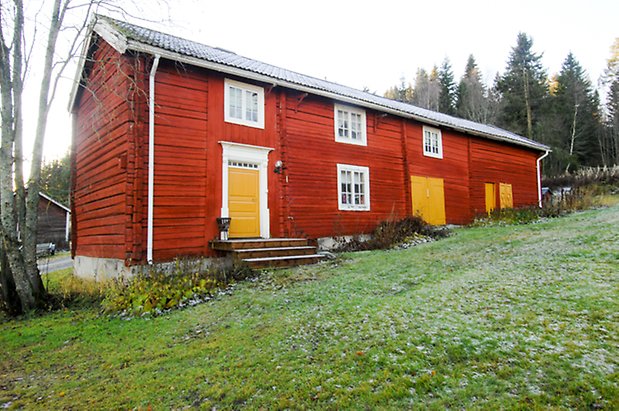 Timrad byggnad i rött i två våningar med gula dörrar och fönster med vita spröjs.