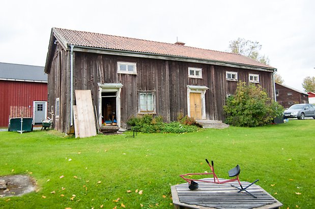 Boda 2:2. Byggnad i grånad panel med två gula dubbeldörrar och fönster med spröjs.