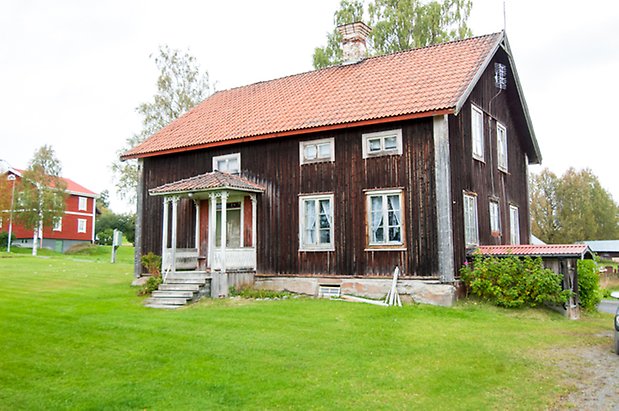 Boda 3:1. Hus i två våningar brun panel med vit förstukvist och fönster med vita spröjs.