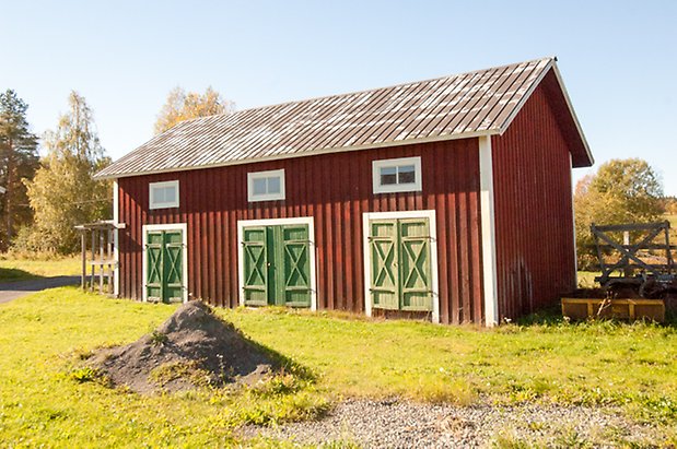 Fjäl 2:17. Byggnad i röd panel med tre gröna dubbelportar.