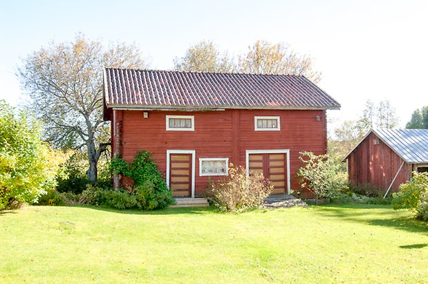 Fjäl 4:34. Timrad, rödmålad byggnad i två våningar, en port och en dubbelport i gult och rött.