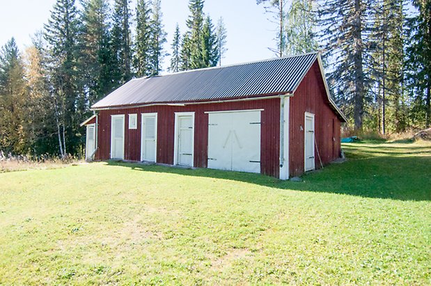 Fjällandet 1:30. Byggnad i röd, stående panel med vita garagedörrar och fem vita dörrar.