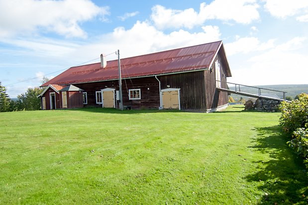 Husås 2:14. Ladugård i brun panel med två gula dubbelportar och två gula dörrar.