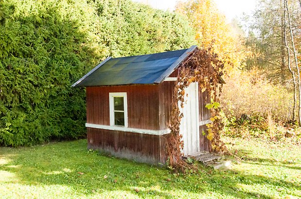 Hölje 1:17. Liten byggnad i röd panel med ett fönster och en vit dörr.