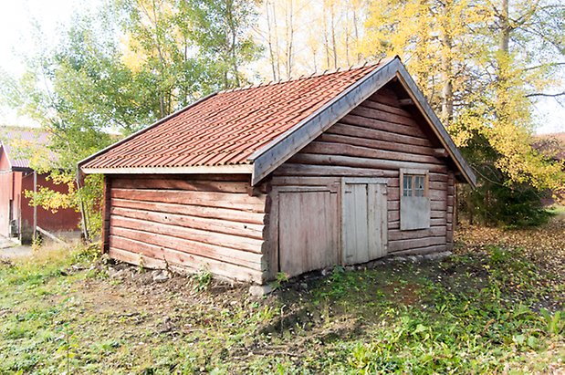 Hölje 1:17. Timrad grå byggnad med två luckor och ett fönster med spröjs.