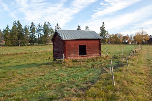 Hölje 3:4. Timrad, röd lada på äng.