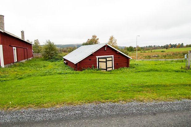 Klösta 2:5. Låg timrad byggnad med gul/svart dörr.