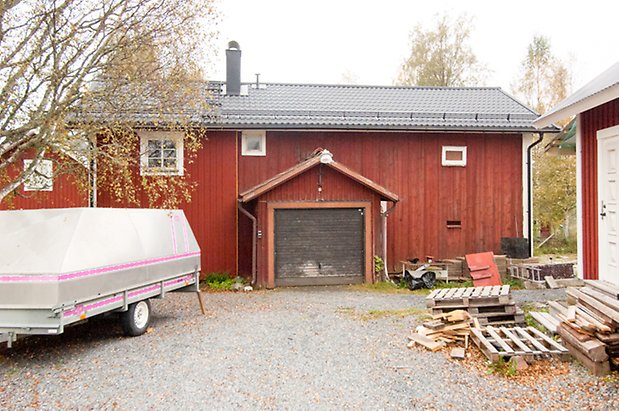 Klösta 5:5. Byggnad i två våningar i röd panel med brun garageport.