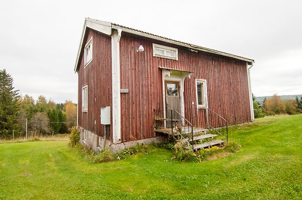 Korsta 2:4. hus i två våningar i röd panel med metalltrapp och brun dörr.