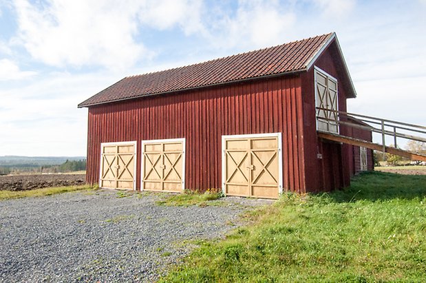 Lits-Bye 1:40. Ladugård i röd panel med fyra gula dubbeldörrar.