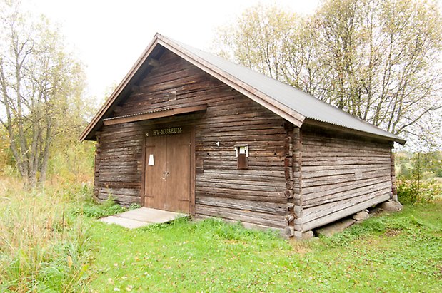 Lits Prästbord 1:18. Grå timrad byggnad med dubbeldörr.