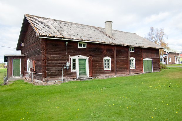 Ringsta 3:26. Timrad, brun byggnad i två våningar med grön dörr och dubbelport, liten tillbyggnad med grön dörr.