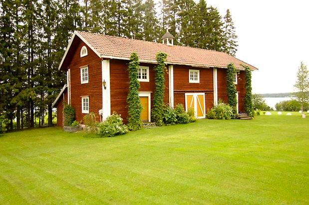 Digernäs 2:7. Byggnad i två våningar i rött timmer, med fönster med vita spröjs och gul och vit dubbeldörr. och gul dörr.