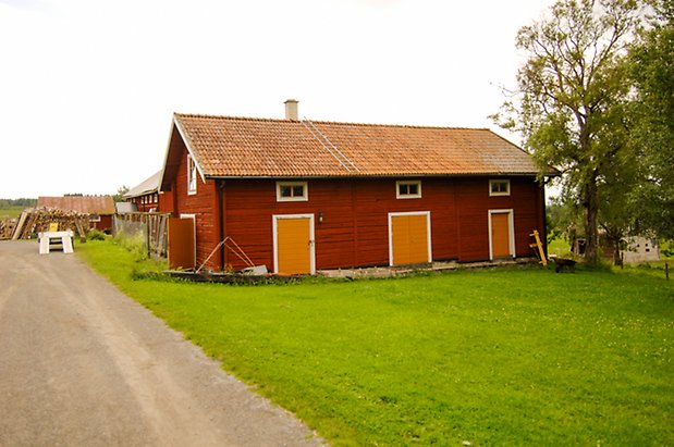 Åkeräng 2:14. Röd, timrad byggnad med en gul dubbelport och två gula portar med små fönster ovanför.