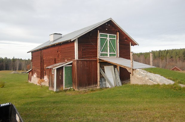 Näs-Viken 1:2. Röd, timrad ladugård med grön dubbelport, lite tillbyggnad i röd panel med grön dörr till vänster. 