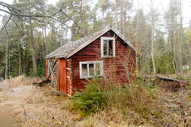 Åsan 1:2. Byggnad i rött timmer med fönster med vita spröjs, trasigt glas.