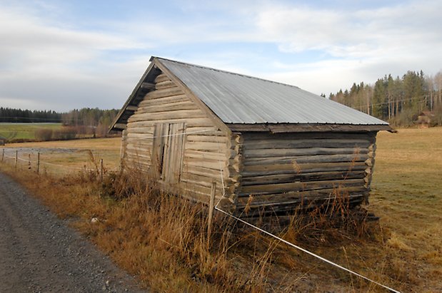 Åsan 1:2. Grå, timrad byggnad.