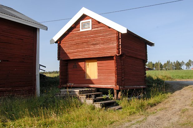 Jälsta 1:3. Timrat, rött härbre med gul lucka och litet fönster med bruna spröjs.