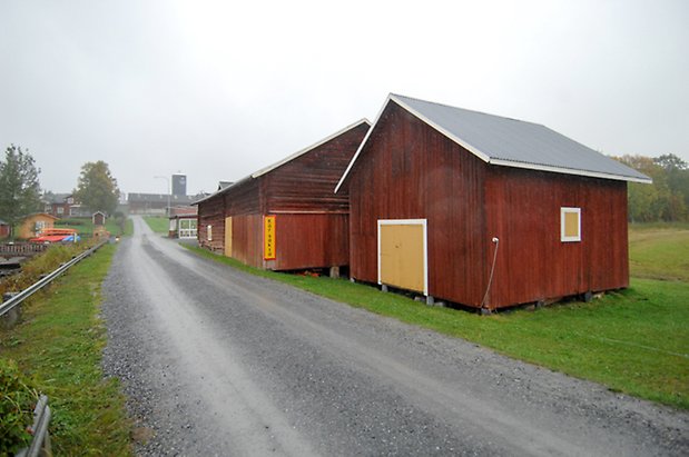 Tivarsgård 4:1. Byggnad i två våningar i röd panel med gul lucka, bredvid en röd byggnad i timmer och panel.