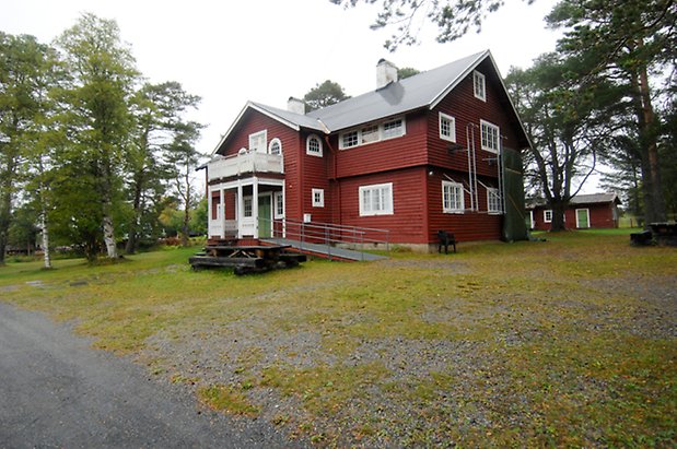 Västanede 2:2. Villa i röd, liggande panel, förstukvist med balkong med snickarglädje, grön dubbeldörr, fönster med vita spröjs.